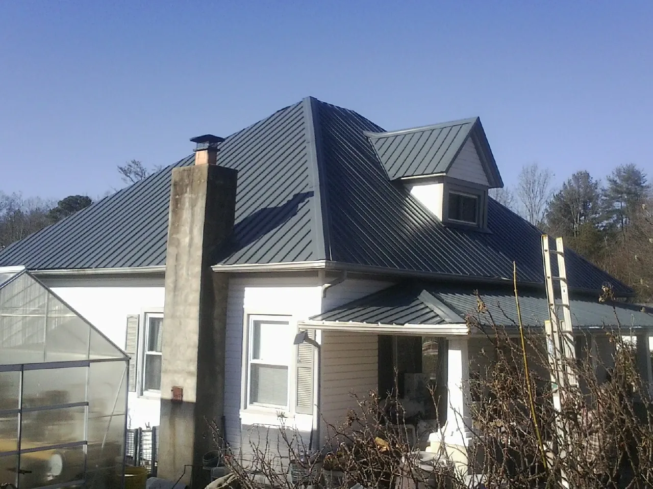 Dark blue standing seam metal roof on a white farmhouse with dormer — Slate & Tile Roof Repair by Roofing Brothers in Randle