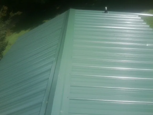 New green metal panels meeting at the ridge of a roof — Flat Roof Repair work by our crew in Randle
