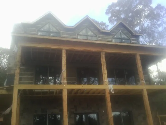 Dormers and porch framing on a large log home under construction — Roof Coating work by our crew in Randle