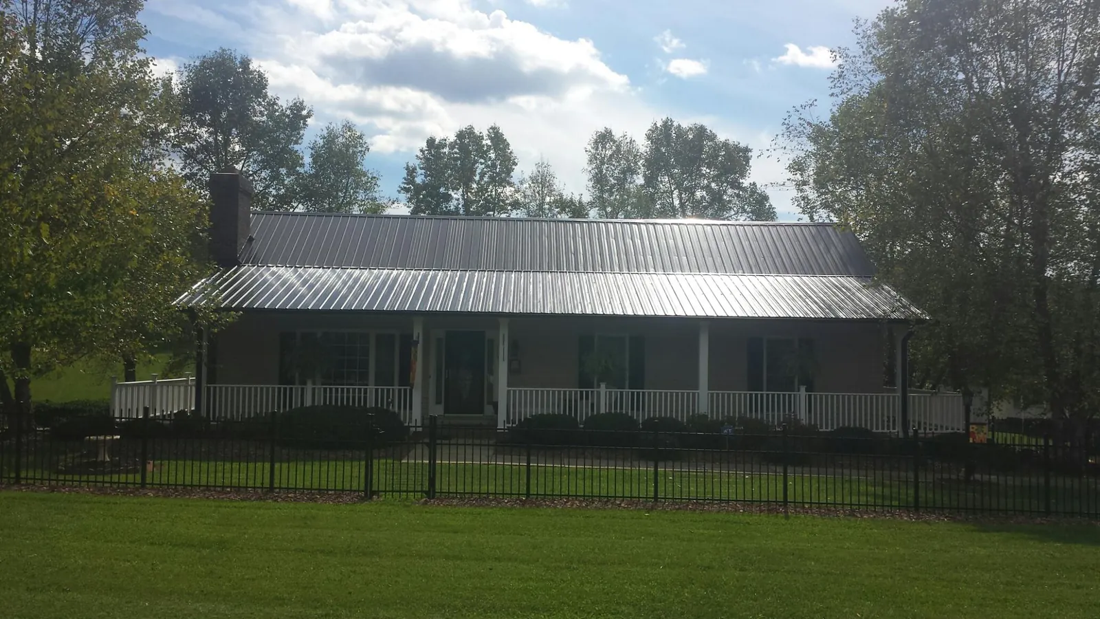 Gray metal roof on a brick ranch with a full width front porch — Gutter Guard Installation work by our crew in Randle
