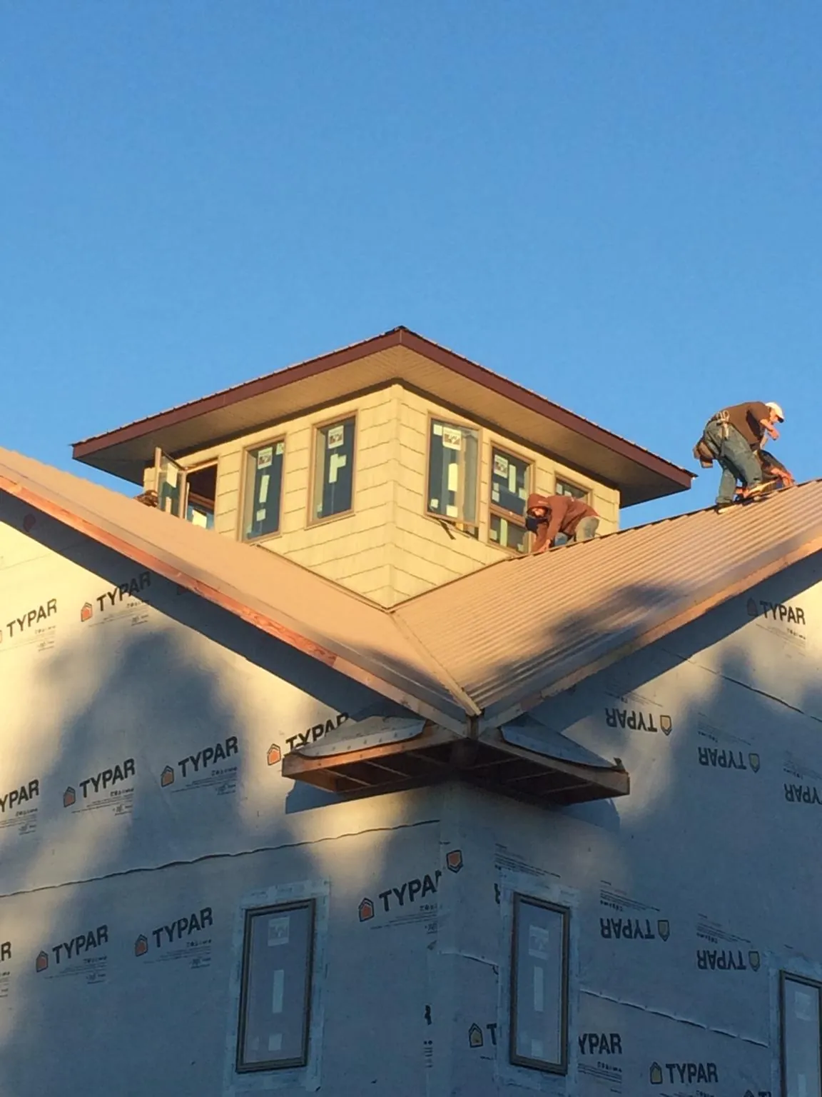 Roofers working around a rooftop cupola on a new metal roof at sunset — Roof Waterproofing in Randle by Roofing Brothers